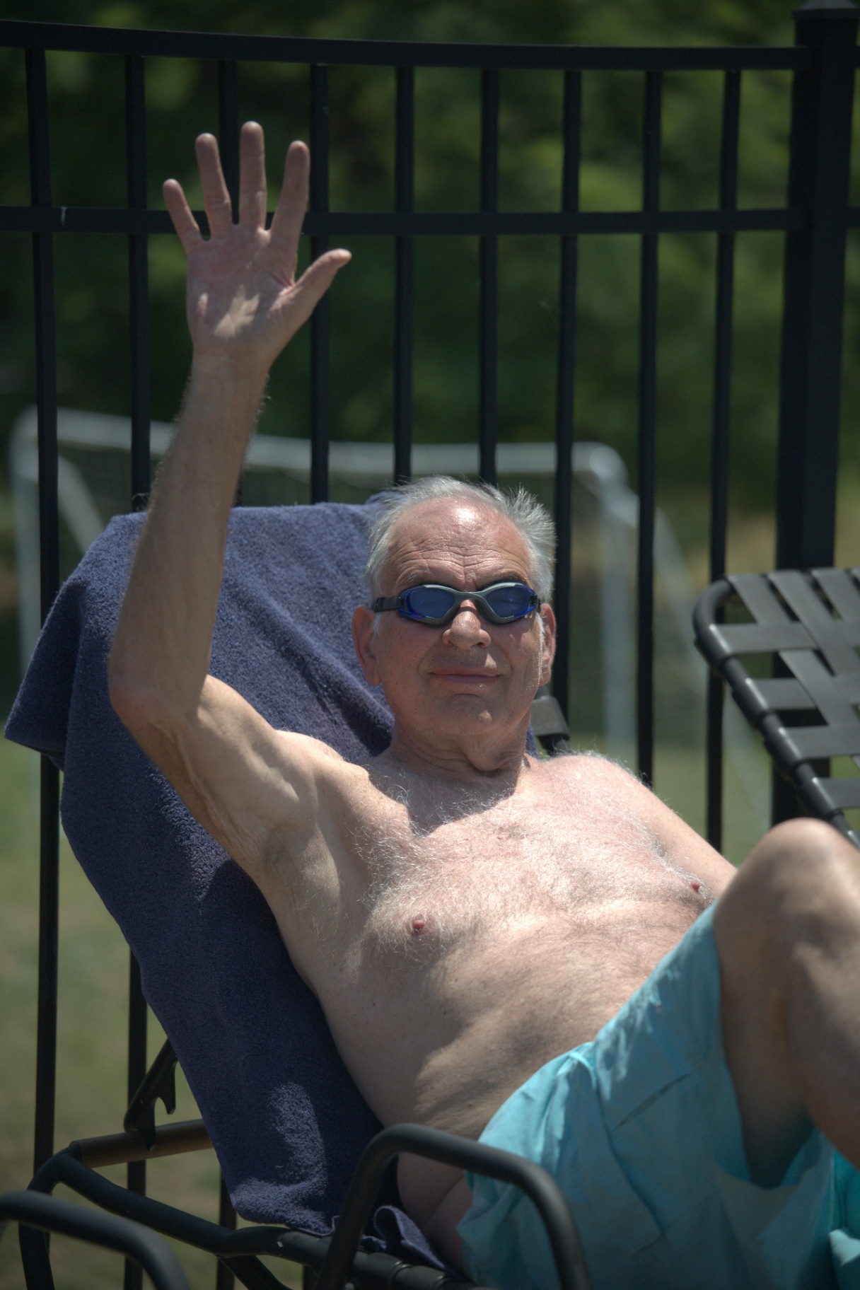 Longtime resident waving from a poolside chair